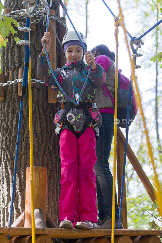十几岁的女孩有乐趣在绳索课程冒险公园。Zipline为孩子。