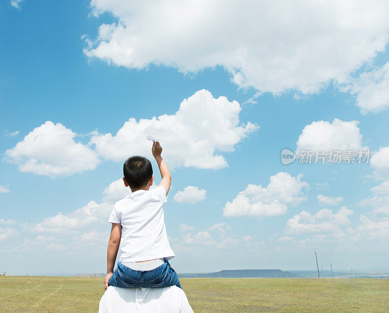 儿子和父亲在田野里玩纸飞机
