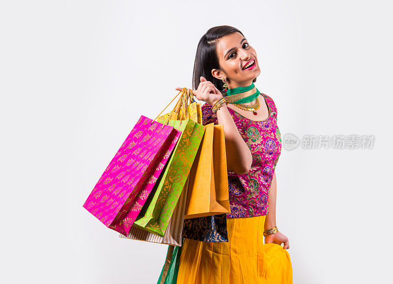 肖像印度年轻快乐的微笑女人购物袋在传统的穿着，孤立在白色的背景