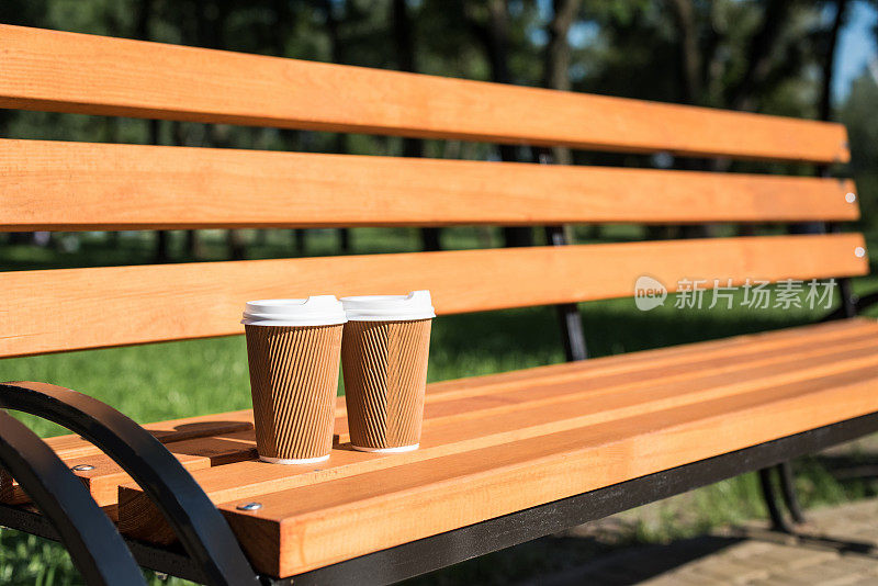公园木凳上的两个一次性咖啡杯的特写