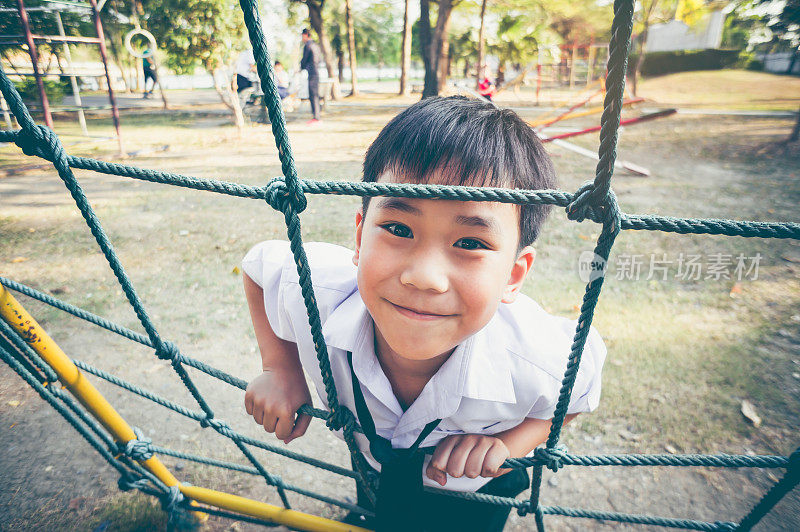亚洲儿童攀登在儿童游乐场的绳子。复古的基调。