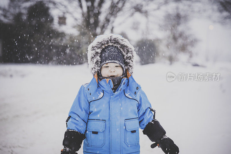 穿着蓝色冬装的小男孩和雪玩