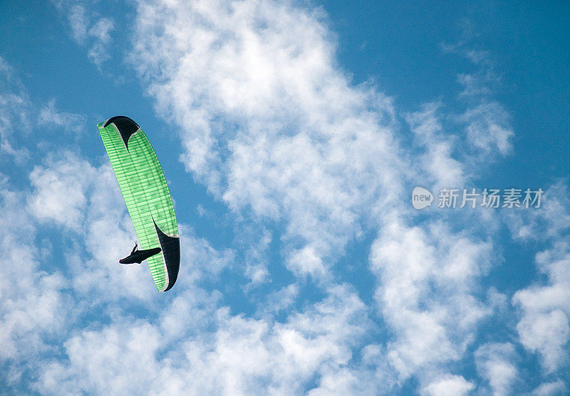 滑翔伞在蓝天中飞行，背景是云。
