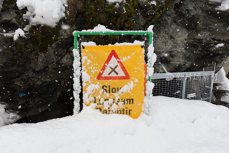 滑雪道上被雪覆盖的减速标志