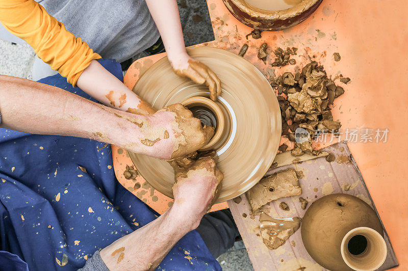 儿童陶工在一个陶器轮上用粘土做一个罐子