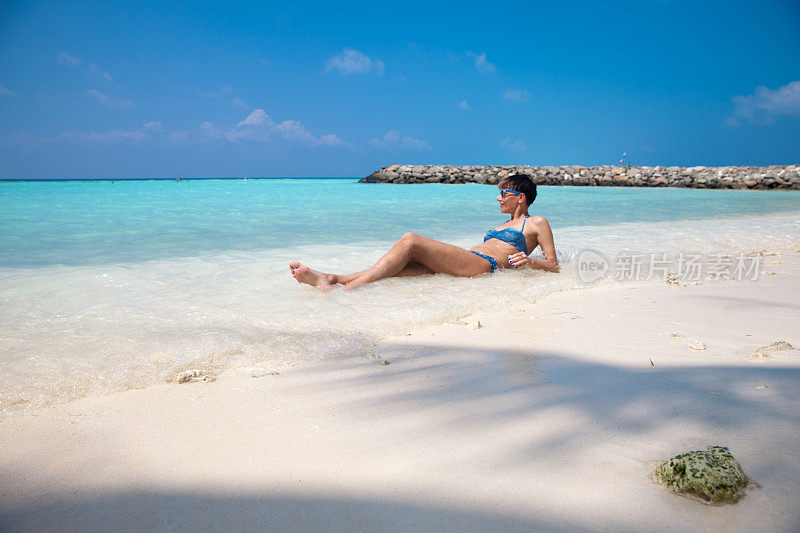 放松的年轻女子享受日光浴在热带海滩