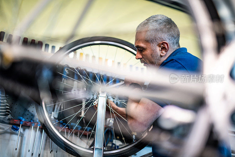 自行车修理工在车间修理一个自行车轮子。