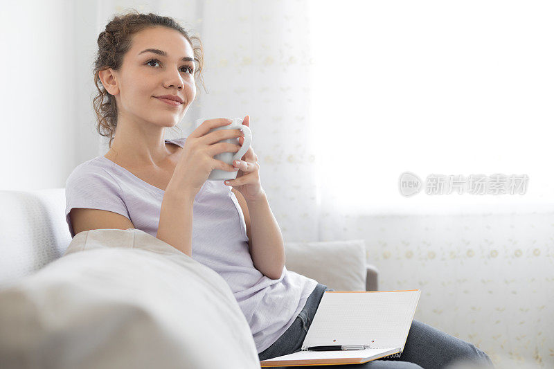 年轻女子坐在沙发上喝茶