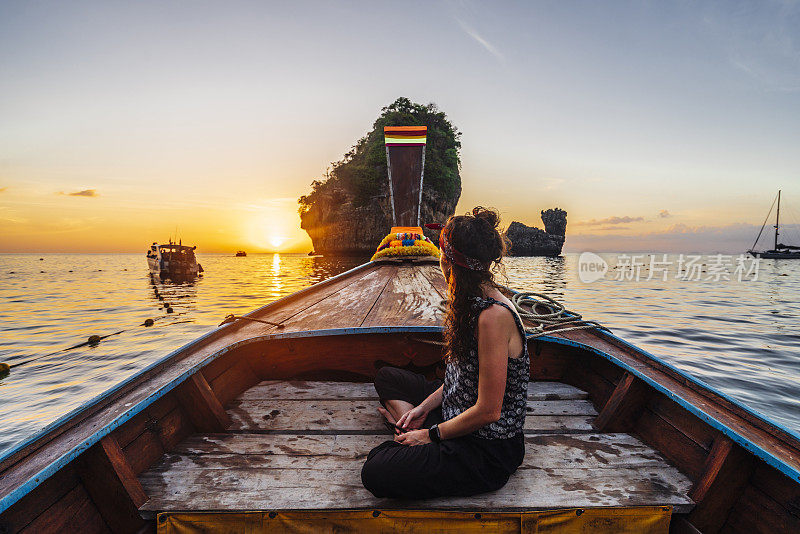 夕阳西下时，在泰国皮皮岛的一艘长尾船上的年轻女子