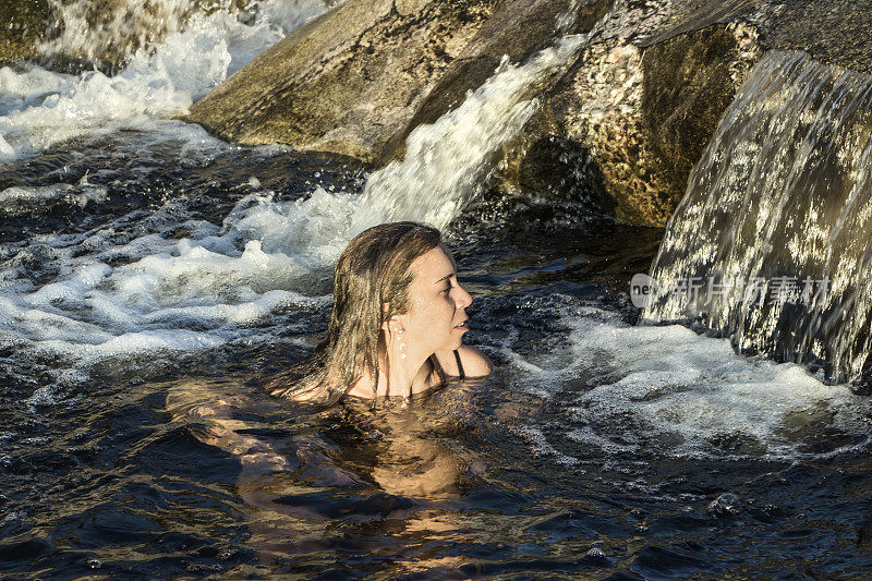 日落时分，这个女人在一条美丽的河里做水疗。米娜·克拉维罗，科尔多瓦，阿根廷。