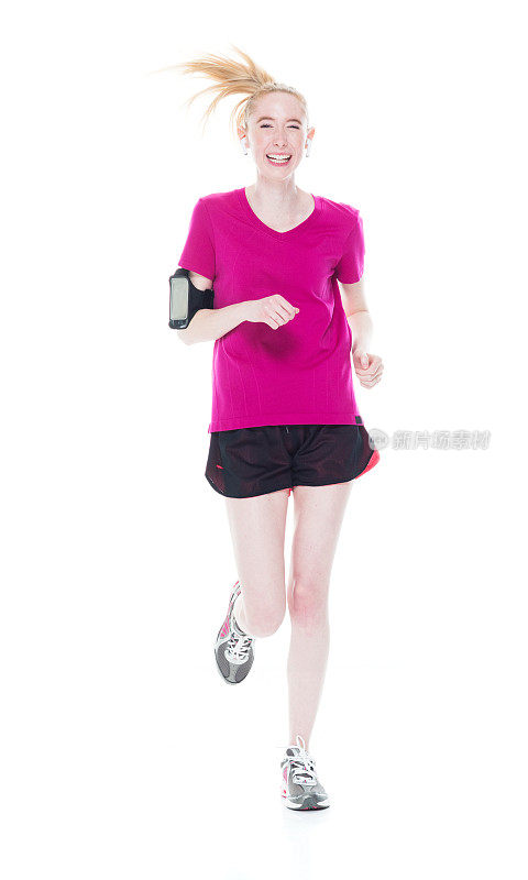 白人年轻女性穿着运动服，戴着耳机跑步