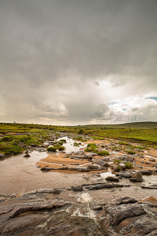 在秋季雨季开始时多云的天空下，靠近肯尼亚-坦桑尼亚边境的马赛马拉的低水位沙河