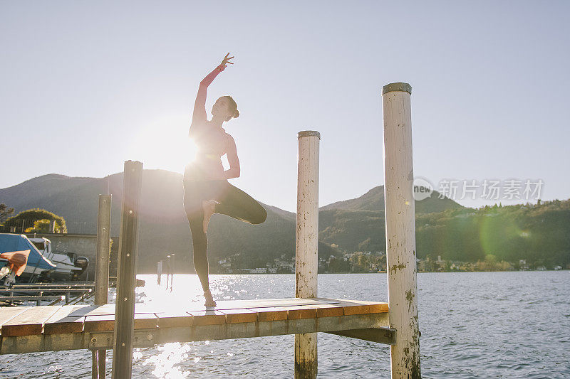 女子在湖边的码头上表演瑜伽动作