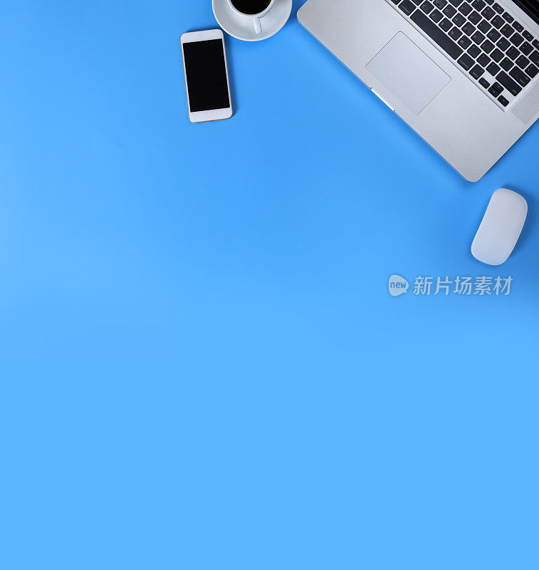 俯视图笔记本电脑，鼠标，智能手机和蓝色背景的咖啡。笔记本电脑，鼠标，手机，黑咖啡孤立的蓝色背景与复制空间横幅。经营理念。