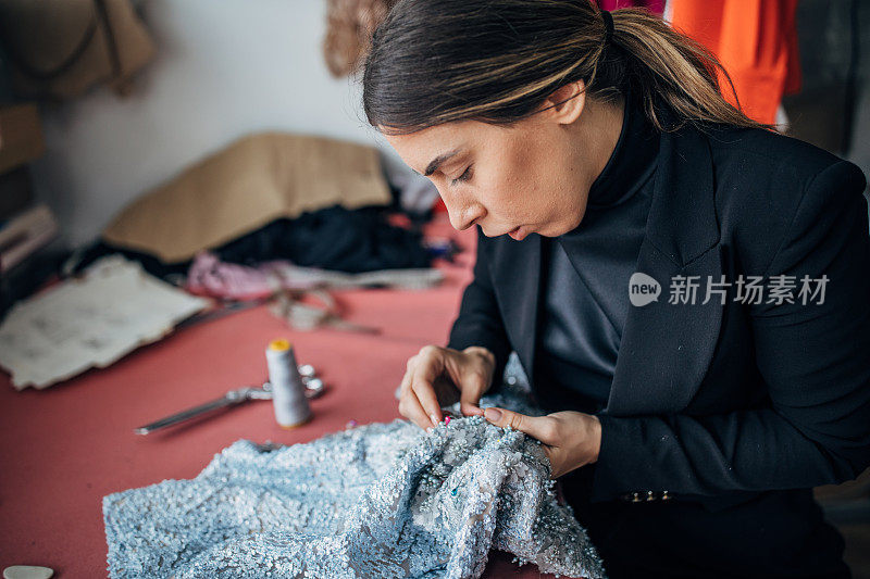 女时装设计师在她的车间里缝纫