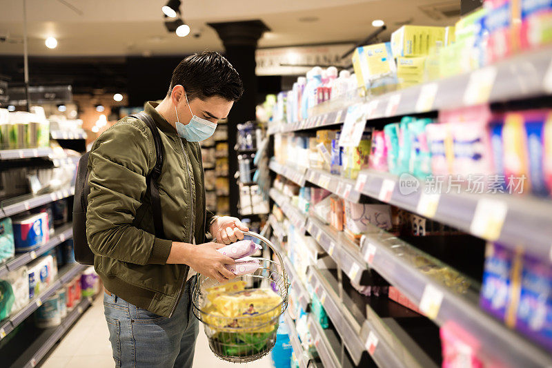 一名戴着口罩的男子在超市里寻找消毒剂