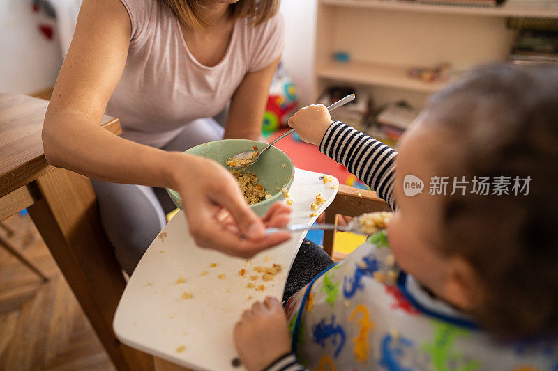 单身母亲在家给蹒跚学步的儿子喂奶