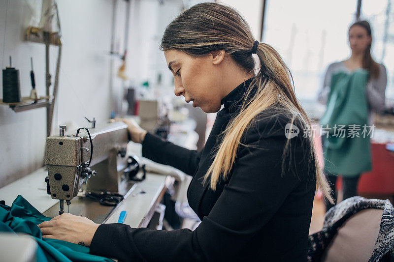 一位年轻的女时装设计师在缝纫机上工作