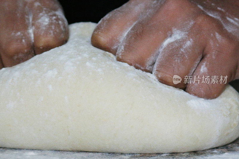 不可辨认的人用手揉面团做面包的特写图像，家庭烘焙的概念