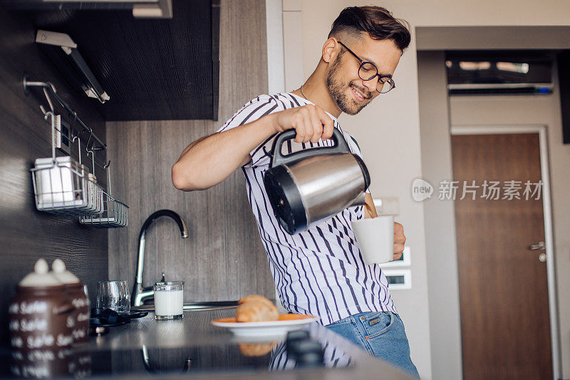 快乐的年轻人在厨房里准备咖啡和早餐