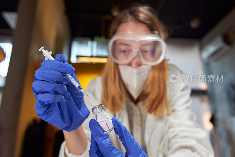 女医生在现代微生物实验室注射疫苗溶液注射器