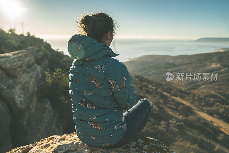 海景和山脉。从悬崖上欣赏史诗般的景色的女人