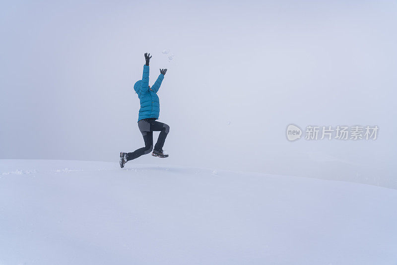 成熟的女人穿着皮大衣在雪地上跳起来