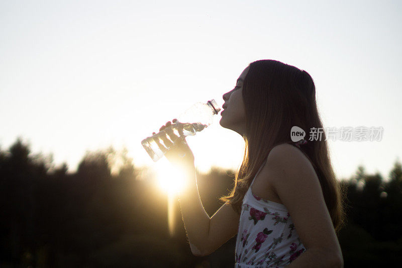 女孩在日落喝水