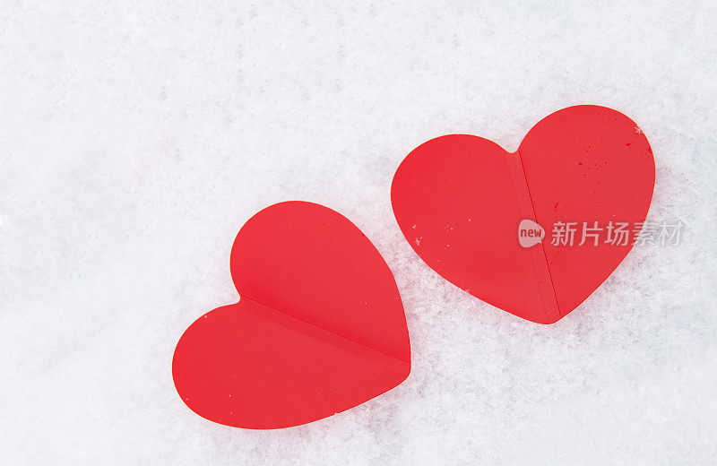 白雪皑皑的背景上，两颗美丽浪漫的红心在一起。爱情和情人节的概念