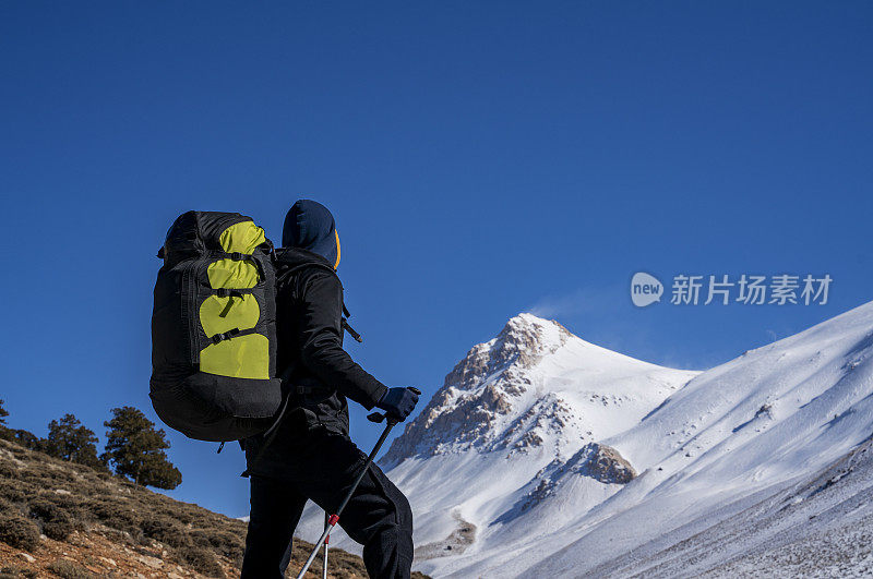 冬天背着降落伞背包在山上徒步旅行的人