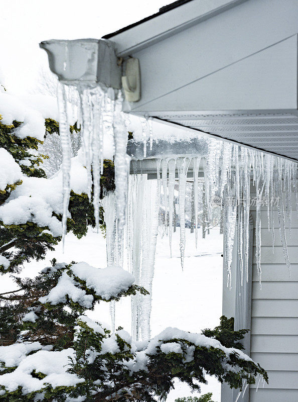 悬挂在屋顶排水沟上的冰冻冰柱