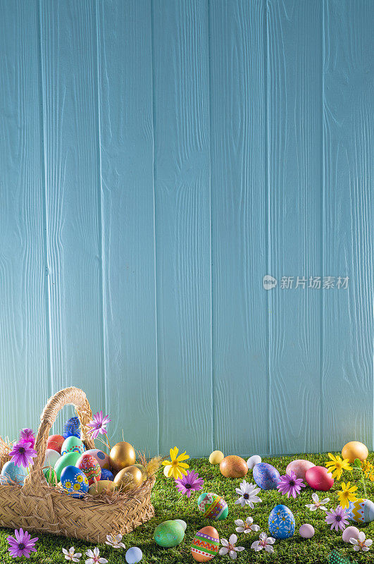 草坪上的复活节彩蛋篮子和蓝色的木墙，春天的花朵