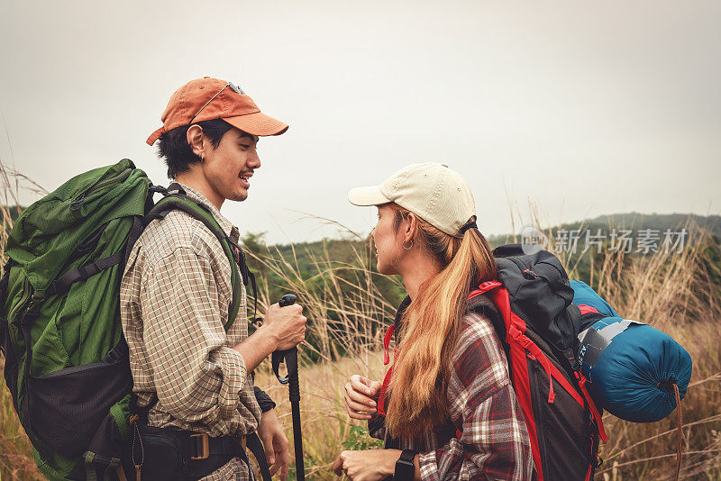 年轻夫妇带着背包在山顶徒步探险，冒险旅行的生活方式