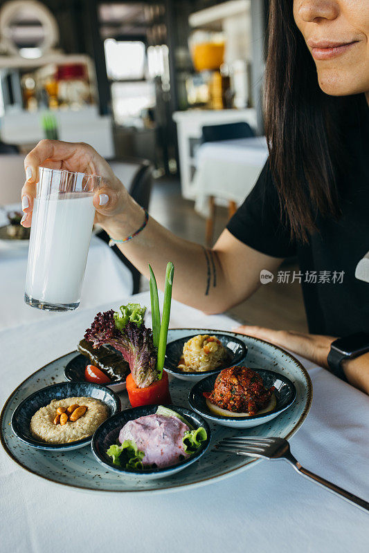 美丽的女人拿着土耳其拉基，在晚餐上吃美味的开胃菜