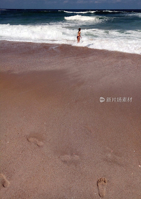 年轻的女孩在阳光明媚的夏日里跳着波浪