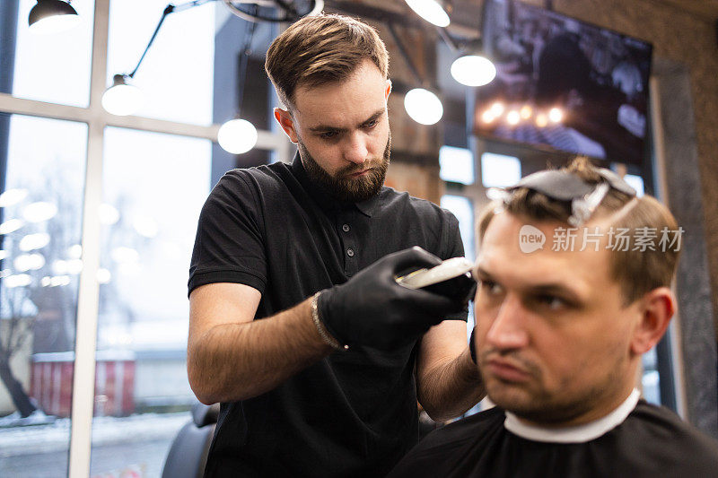 师傅在理发店为男士理发，理发师为年轻人理发