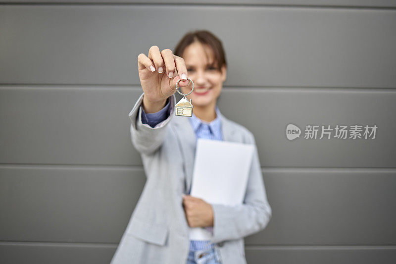 模糊肖像的年轻女房地产经纪人手里拿着钥匙