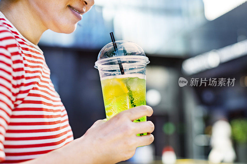 用塑料杯盛着柠檬水的女人的手