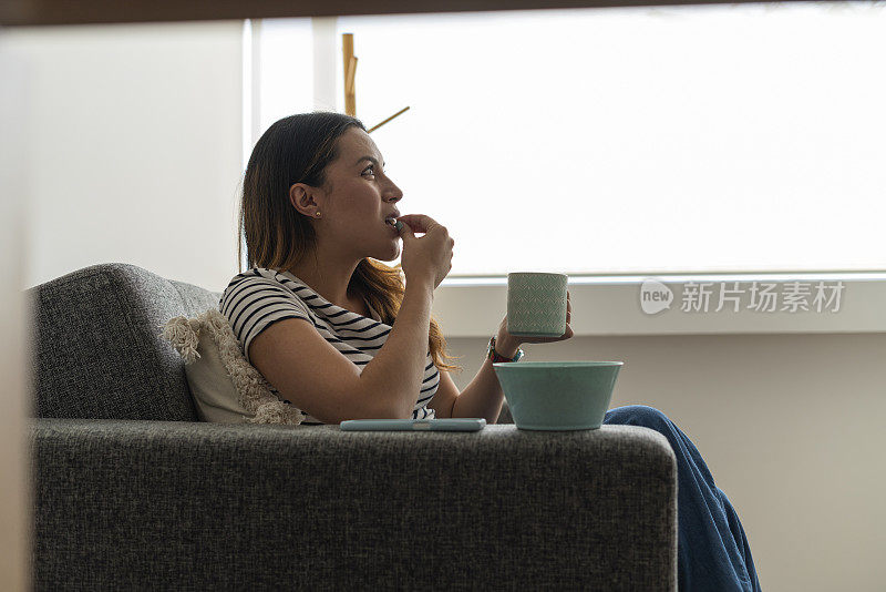 一位拉丁妇女在舒适的家里聚精会神地看电视连续剧