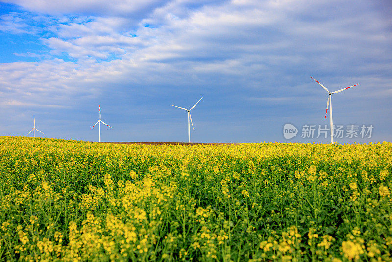 多云的天空下，农田上一排排的风力涡轮机