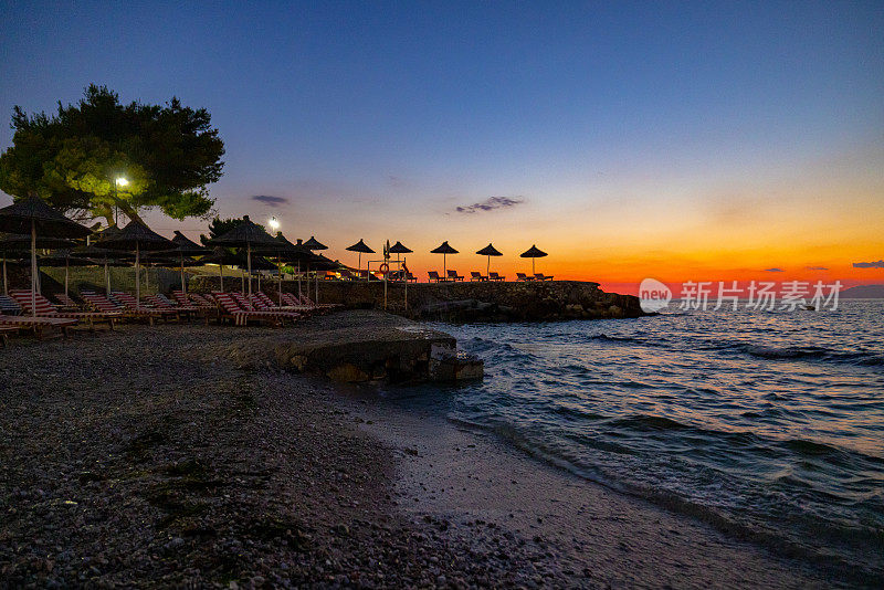 日落时，度假胜地的躺椅上海浪冲向海滩的风景