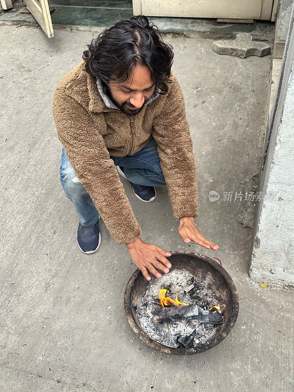 印度人温暖的手在卡代(印度火碗)与舞蹈的火焰，灰烬和烟雾，燃烧的木材余烬，上升的观点，重点在前景