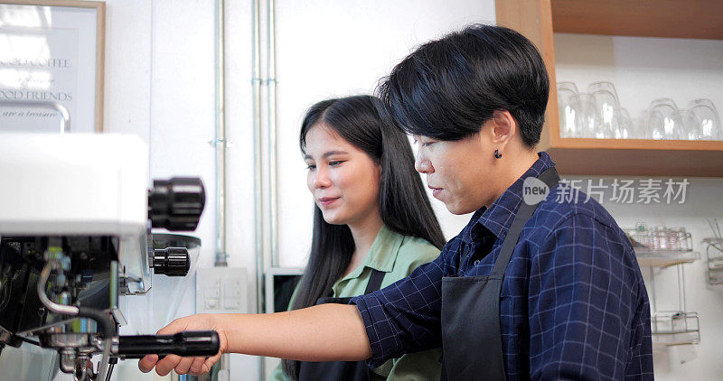 两名穿着围裙的亚洲妇女在咖啡馆里交谈并教授如何使用咖啡机