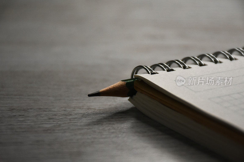 螺旋笔记本和一支笔在木桌上
