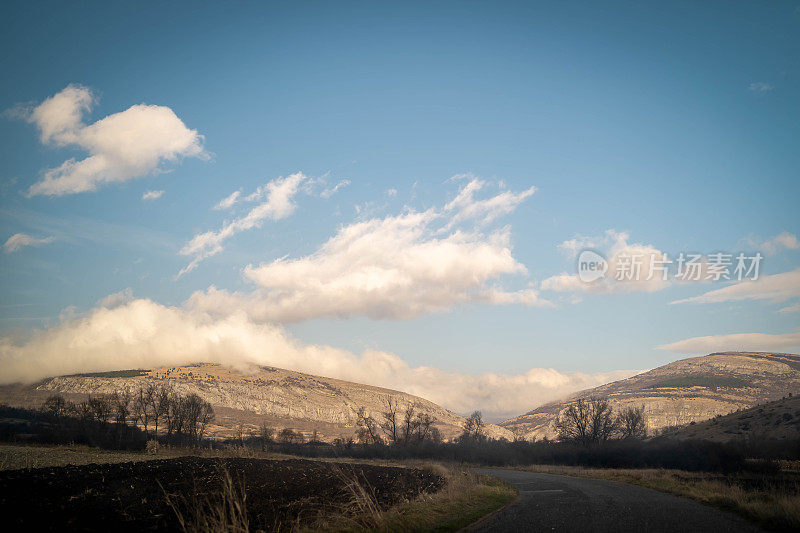 空旷的柏油路在乡村景观在日落与戏剧性的云