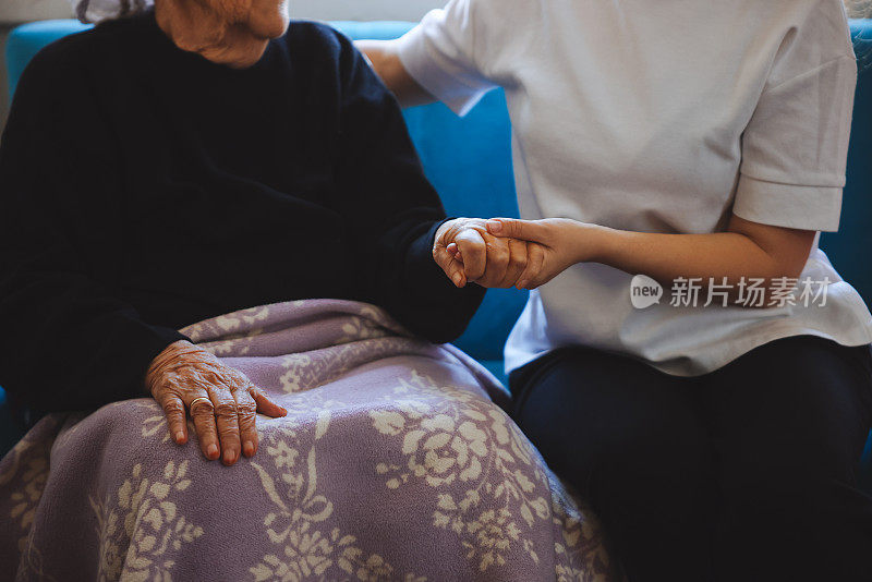 老女人的手牵着年轻女人的手，伸出援手，照顾老人的理念。