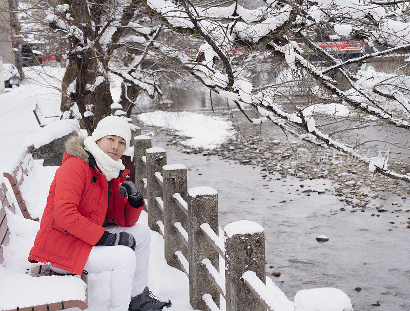 在下雪的冬天，游客们坐在那里享受他们的日本之旅。