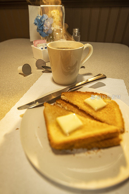 在日出时分的餐厅里，一杯热气腾腾的咖啡和黄油烤面包