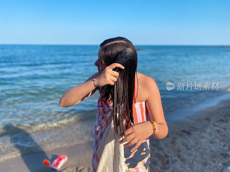 一个十几岁的小女孩在沙滩上梳头