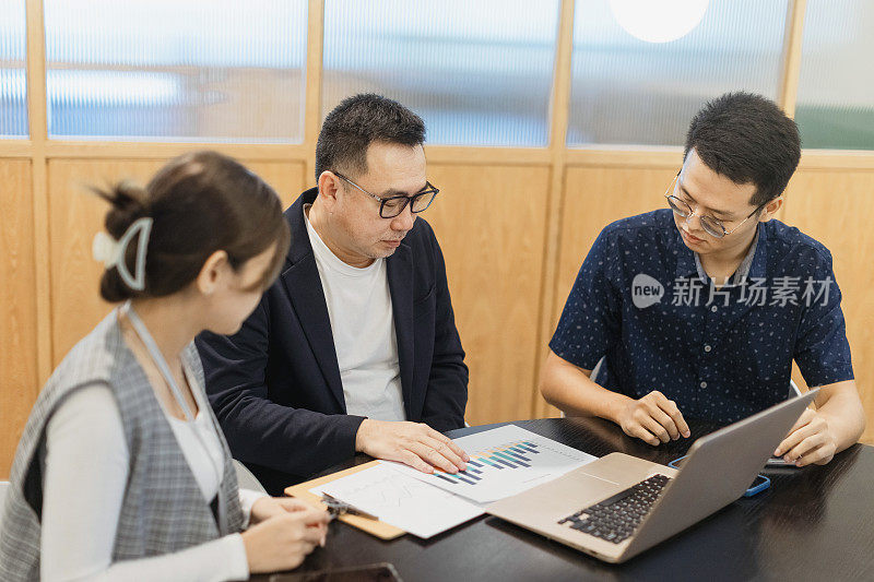 一位亚洲商人正在办公室会议室用笔记本电脑和他的同事开会。库存图片